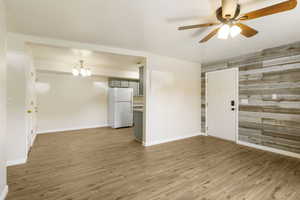 Foyer featuring a ceiling fan, wood finished floors, baseboards, and a chandelier