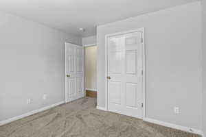 Unfurnished bedroom featuring carpet, baseboards, and a textured ceiling