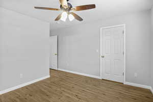 Empty room with wood finished floors, ceiling fan, and baseboards