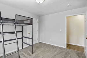 Unfurnished bedroom with carpet flooring, baseboards, and a textured ceiling