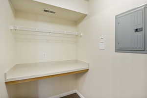 Walk in closet featuring electric panel, built in desk, and dark wood-style flooring