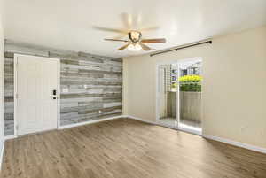 Spare room featuring a ceiling fan, an accent wall, baseboards, and wood finished floors