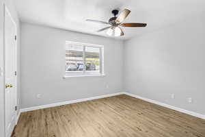 Spare room with light wood-style floors, baseboards, and ceiling fan