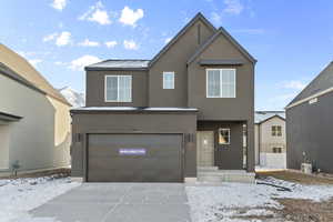 Traditional-style house featuring an attached garage, concrete driveway, and stucco siding