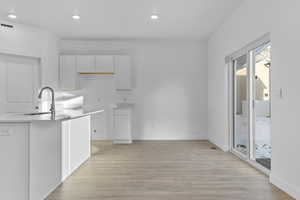 Kitchen with a sink, healthy amount of natural light, recessed lighting, light wood-style flooring, and white cabinetry