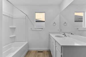 Full bath featuring healthy amount of natural light, baseboards, wood finished floors, and vanity