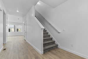 Stairway with wood finished floors, baseboards, and recessed lighting