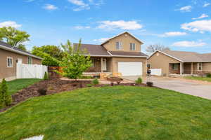 Traditional home featuring a garage, driveway, stucco siding, a gate, and covered porch