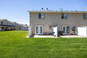 Back of property featuring french doors, a patio, a yard, and stucco siding