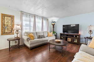 Living area featuring hardwood / wood-style flooring, a textured ceiling, and baseboards