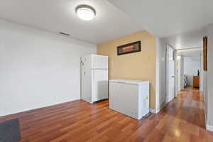 Kitchen featuring freestanding refrigerator, wood finished floors, baseboards, and light countertops