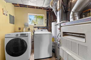 Laundry area featuring washing machine and clothes dryer, heating unit, electric panel, and water heater
