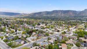 Aerial view of property and surrounding area featuring mountains and nearby suburban area