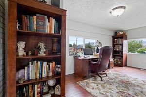 Office or bedroom with a textured ceiling, healthy amount of natural light, wood finished floors, and baseboards