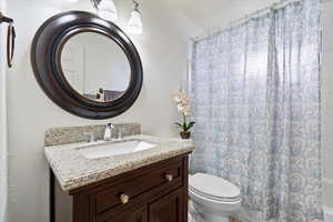 Bathroom with toilet, vanity, and shower / tub combo with curtain