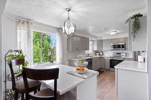 Kitchen with appliances with stainless steel finishes, gray cabinets, a textured ceiling, plenty of natural light, and decorative backsplash