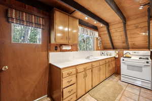 Kitchen featuring white range with gas cooktop, wood ceiling, a sink, and light countertops