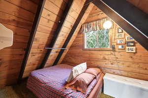 Bedroom featuring wooden walls and carpet floors