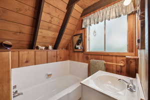 Full bathroom with wood ceiling, wooden walls, a sink, and a bath