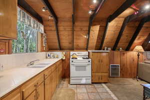 Kitchen with gas range gas stove, tile countertops, a sink, heating unit, and wood ceiling