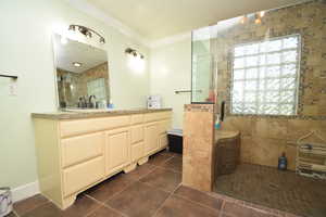 Bathroom featuring a stall shower, ornamental molding, tile patterned floors, and vanity