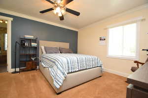 Bedroom with carpet, baseboards, crown molding, and a ceiling fan