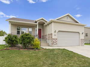 Ranch-style home featuring driveway, brick siding, a garage, a front yard, and a porch