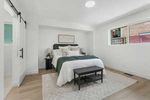 Bedroom featuring a barn door, light wood finished floors, and baseboards