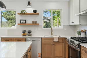 Kitchen with stainless steel appliances, a sink, light countertops, and tasteful backsplash