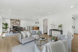 Living room with light wood finished floors, recessed lighting, a stone fireplace, and baseboards