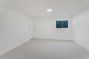 Unfurnished room with baseboards and light colored carpet