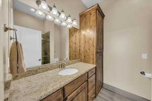 Full bathroom with toilet, a shower, vanity, baseboards, and wood finished floors