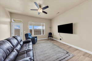 Living area with wood finished floors, a ceiling fan, and baseboards