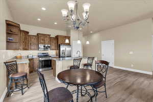 Dining space with light wood finished floors, baseboards, a chandelier, and recessed lighting