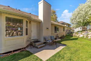 Back of house with stucco siding, a patio, a chimney, and a shingled roof