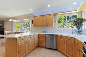 Kitchen featuring dishwasher, light countertops, a peninsula, healthy amount of natural light, and ornamental molding