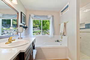 Bathroom featuring a bath, vanity, and tiled shower