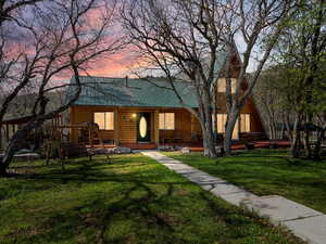 View of front of house with faux log siding, metal roof, a front lawn, and a porch