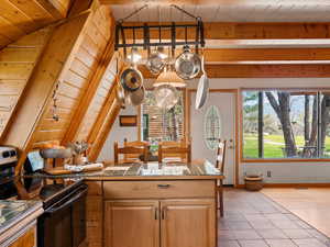 Kitchen with black / electric stove, tile countertops, light tile patterned floors, wooden ceiling, and a chandelier