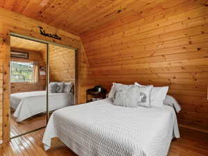 Bedroom featuring hardwood / wood-style floors, a closet, wooden ceiling, and wood walls