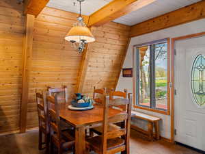 Dining room with beamed ceiling, wooden walls, and wood ceiling