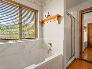 Full bathroom with wood finished floors, a bath, and a shower stall