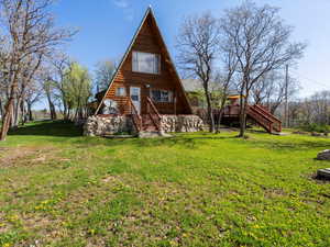 Rear view of house featuring stairs, a yard, a wooden deck, and log siding