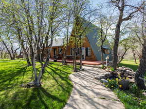 A-frame style home featuring a deck, metal roof, log exterior, and a front lawn