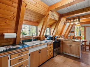 Kitchen featuring electric range, a sink, tile counters, wooden ceiling, and a peninsula