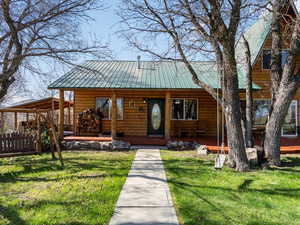 View of front of home with a porch, log veneer siding, and a front lawn