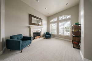 Sitting room featuring carpet, a fireplace with raised hearth, and baseboards