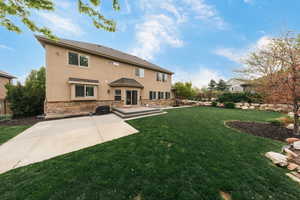 Back of property with stucco siding, stone siding, and a patio