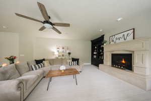 Carpeted living area with a ceiling fan, a high end fireplace, recessed lighting, and baseboards