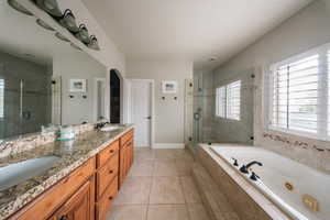Bathroom featuring a shower stall, a whirlpool tub, double vanity, tile patterned floors, and baseboards